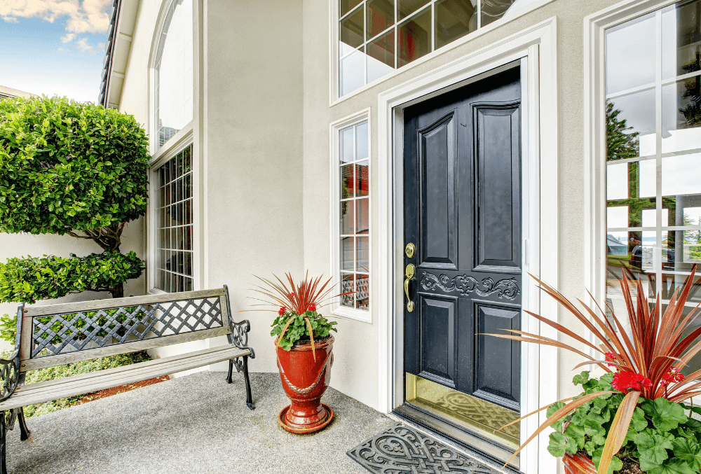 residential home entryway with black door and a flowery plants