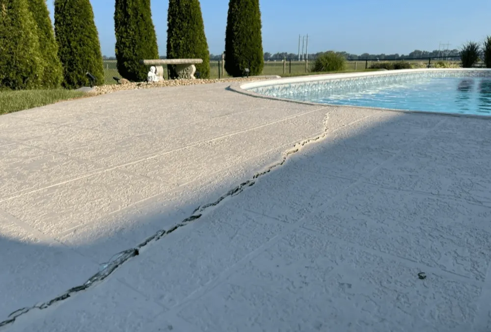 Visible cracks on a concrete pool deck surface