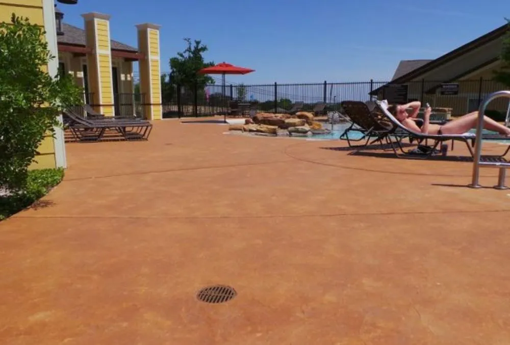 Stained concrete pool deck with rich color tones surrounding a backyard pool in San Jose.