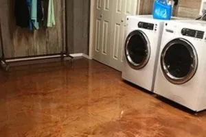 Laundry room with a glossy stained concrete floor beside a washer and drye